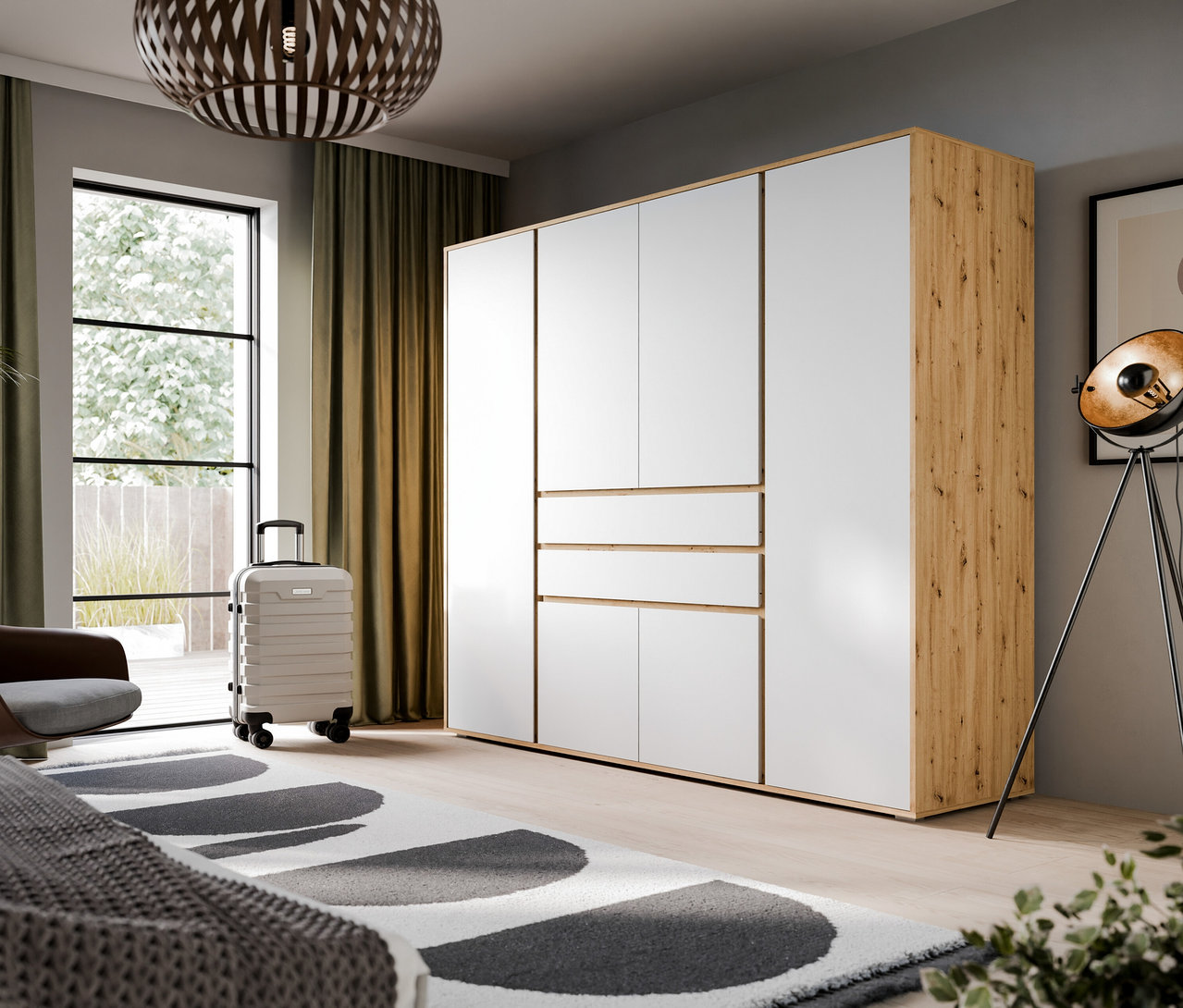 Ein xonox Kleiderschrank »Mora« mit 4 Türen in Eichenoptik-weiß steht in einem modernen Schlafzimmer neben einem Fenster mit Vorhängen und einem Rollkoffer.