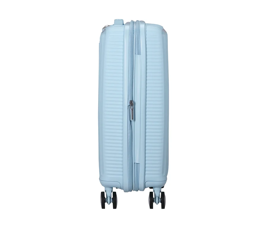 Kleiner, pastellblauer American Tourister Soundbox Hartschalen-Koffer steht aufrecht, von der Seite gesehen, mit gerippter Textur und zwei schwarzen Spinner-Rädern.