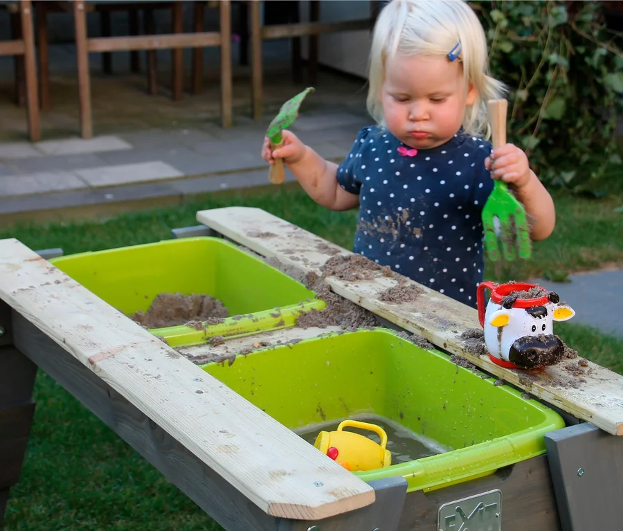 Kleinkind spielt am EXIT Spieltisch mit Bank »Aksent« mit Sand.
