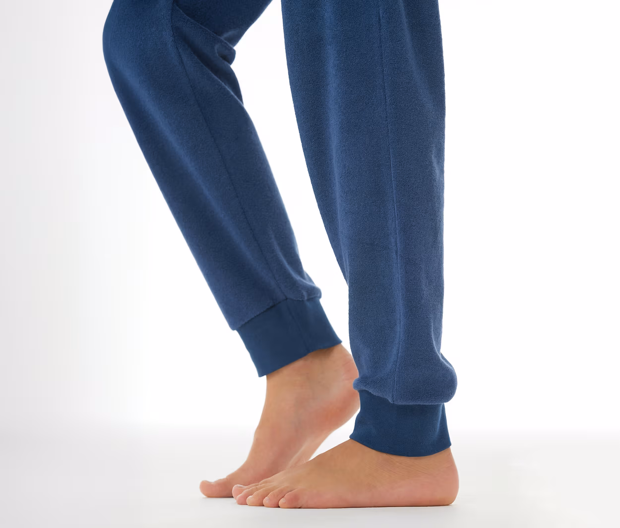 Person trägt eine dunkelblaue SCHIESSER Kinder-Pyjamahose mit Bündchen; die nackten Füße sind sichtbar.