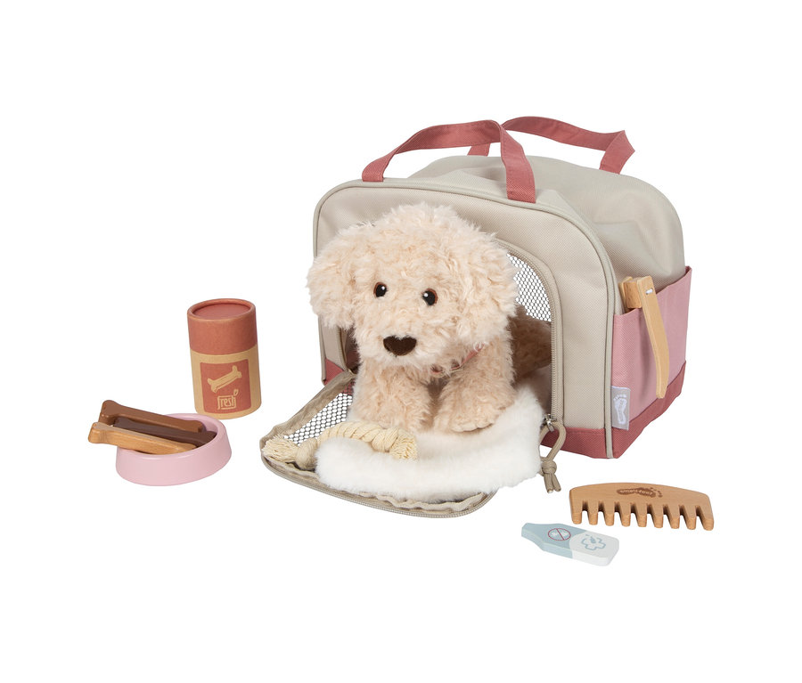 small foot Plüschhund mit Tasche und Pflege-Set. Ein hellbeiger Plüschhund sitzt in einer offenen beige-rosa Tiertransporttasche. Daneben liegen ein rosa Napf mit Holzknochen-Leckerlis, ein Leckerli-Behälter, ein Holzkamm, ein Holzthermometer und eine Bürste in der Seitentasche der Transporttasche.