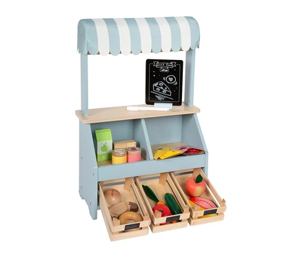 small foot kompakter Kaufladen, ein hellblauer Holz-Marktstand mit gestreifter Markise, der eine Tafel, Holz-Brot, Gemüse und Obst in Kisten zeigt.