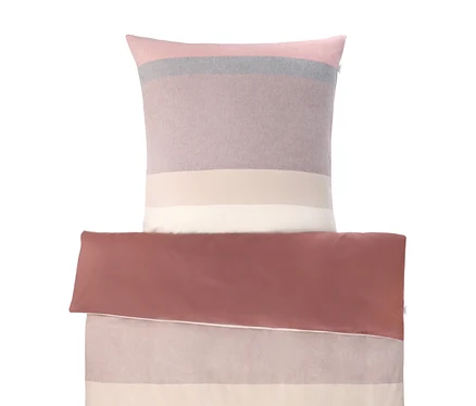 Flanell-Bettwäsche der SCHÖNER WOHNEN-Kollektion mit Kissen und gefaltetem Bettbezug. Kissen und Oberseite des Bezugs sind gestreift in Rosa, Grau, Mauve, Hellbeige und Weiß. Die Unterseite ist einfarbig Rotbraun.