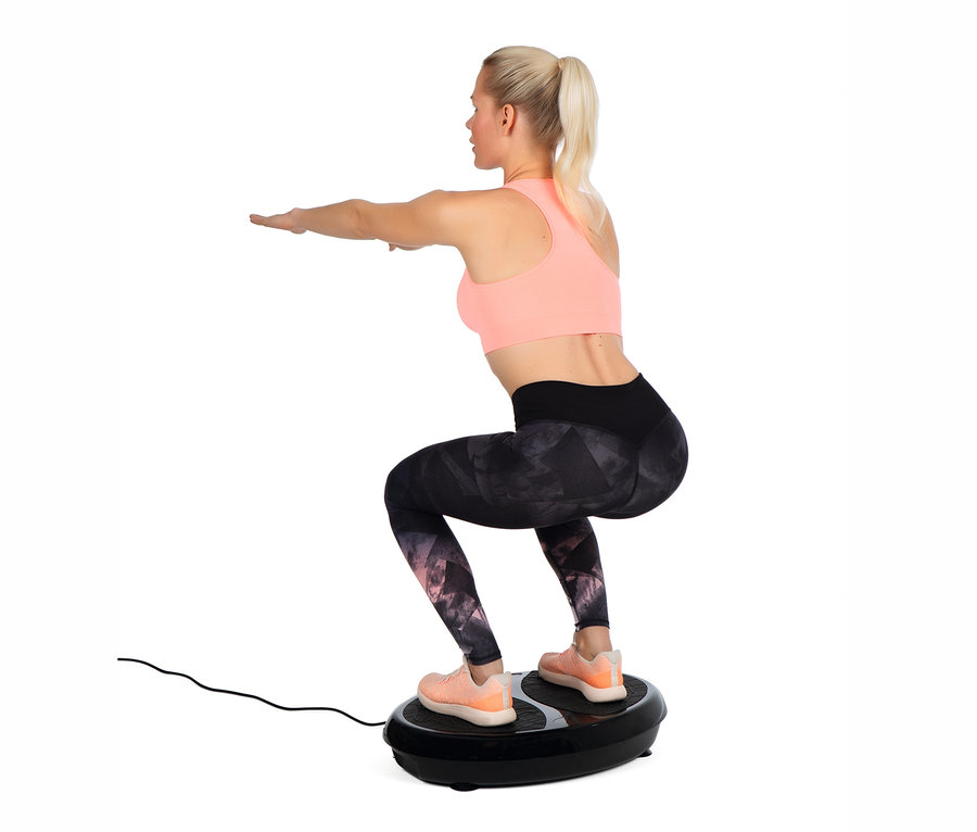 Blonde Frau macht Kniebeugen auf einem VITALmaxx Vibrationstrainer.