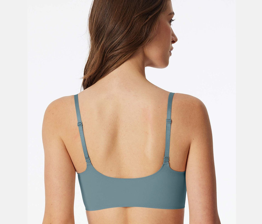 Rückansicht einer Frau mit braunen Haaren, die einen blauen BH trägt.