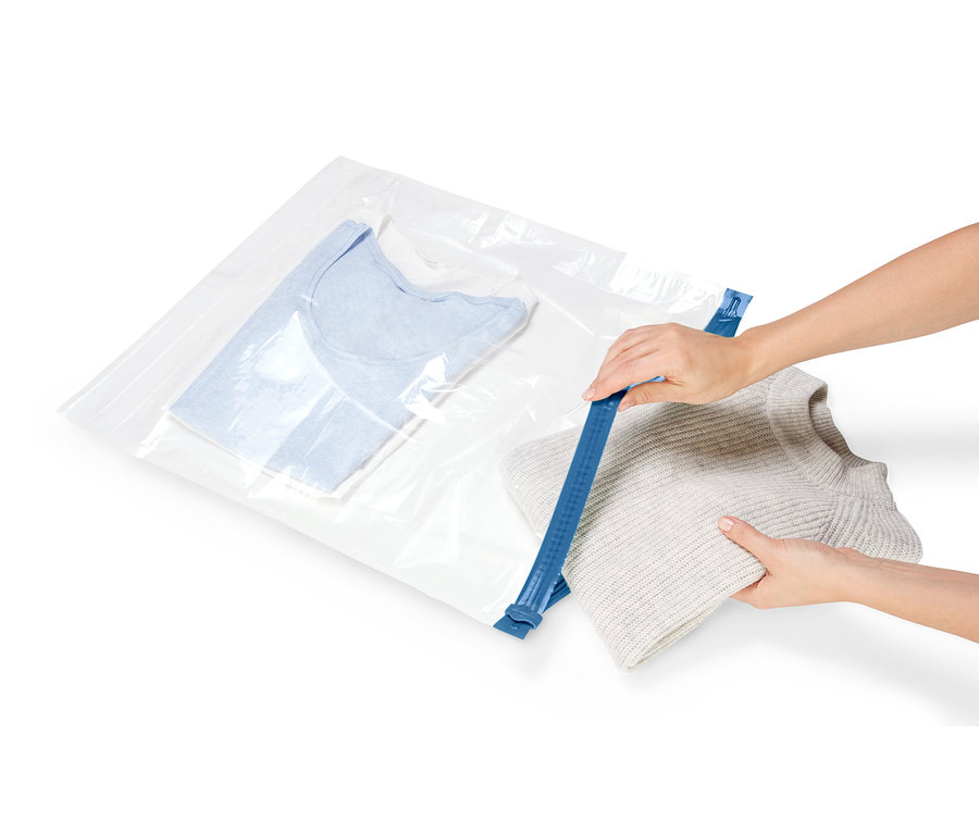Hände verschließen einen 3 Reisebeutel mit Kleidung mit einem blauen Reißverschluss.
