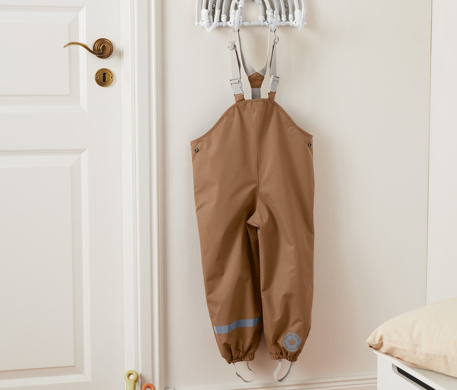 Eine braune Thermo-Regenhose hängt an der Wand.