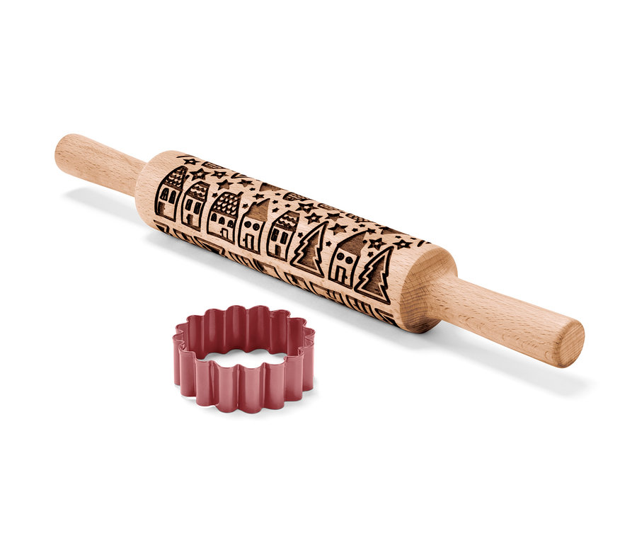 Eine Motiv-Teigrolle aus Holz liegt neben einem Ausstecher.