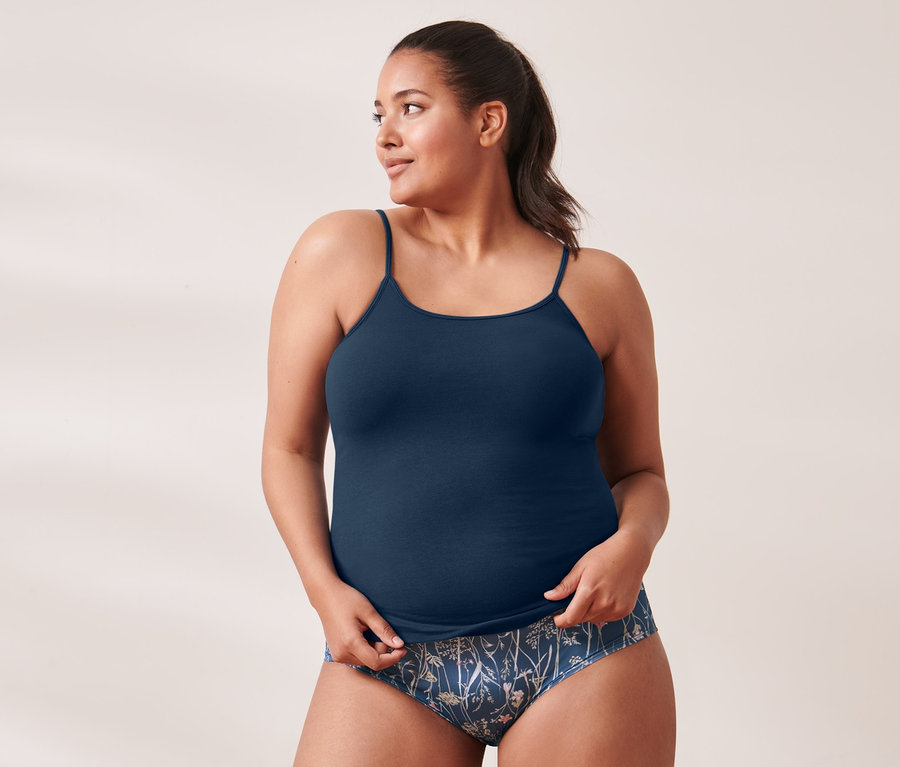 Frau trägt marineblaues 5 Hemdchen und 5 Pantys mit Blumenmuster.