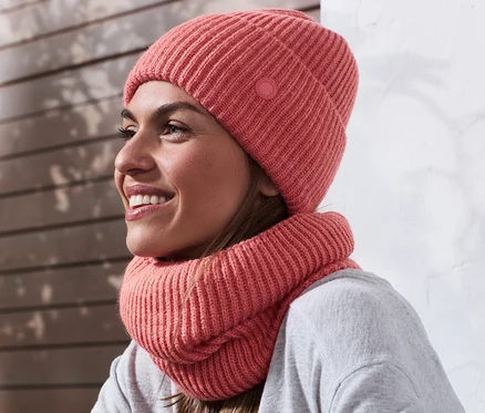 Frau trägt eine roséfarbene Strickmütze.