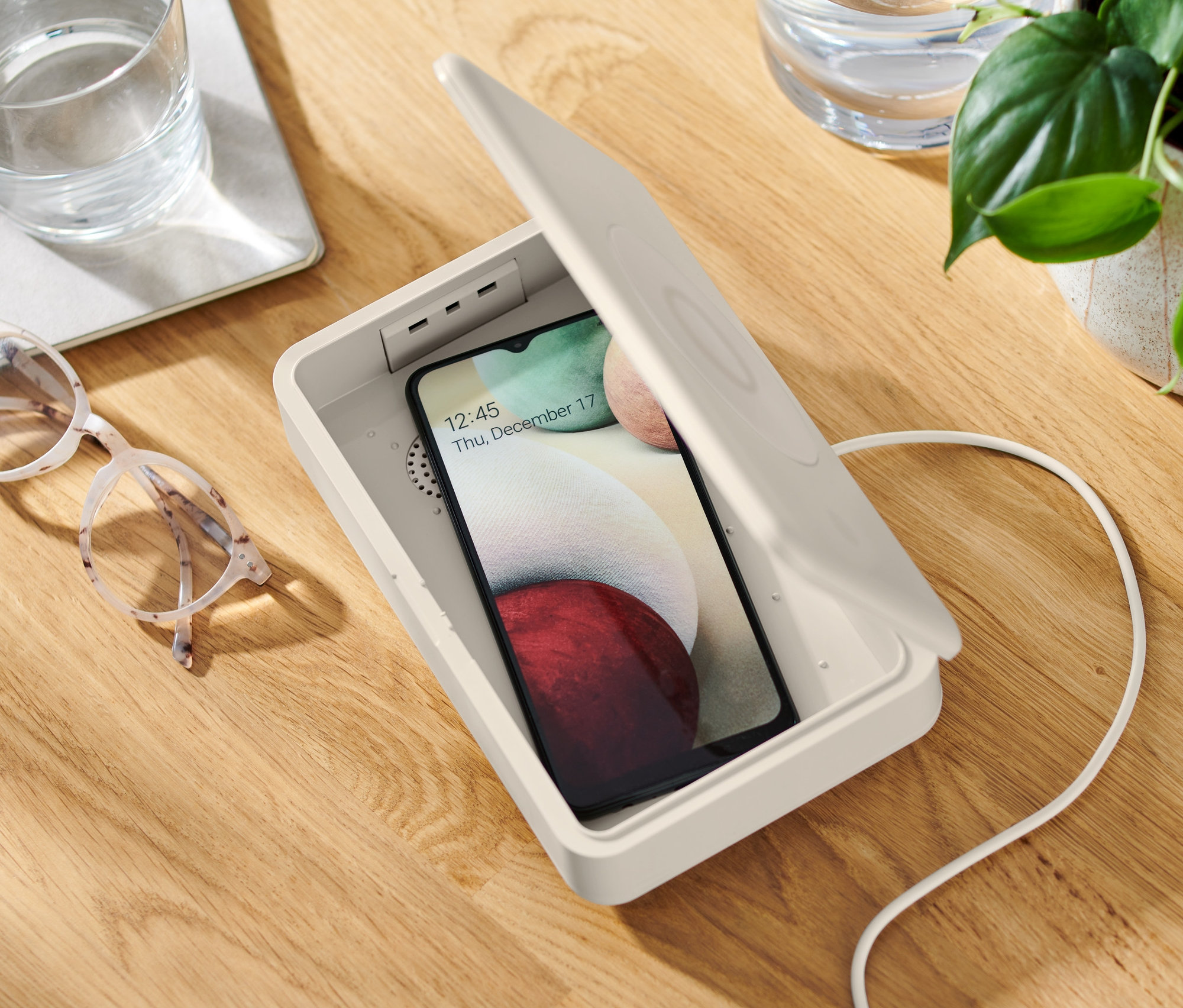 Ein Handy liegt in einer geöffneten UV-Desinfektionsbox mit kabellosem Ladegerät.