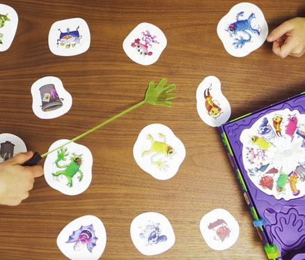 Kinder spielen das Spiel Ravensburger »Monsterstarker Glibberklatsch« auf einem Holztisch.