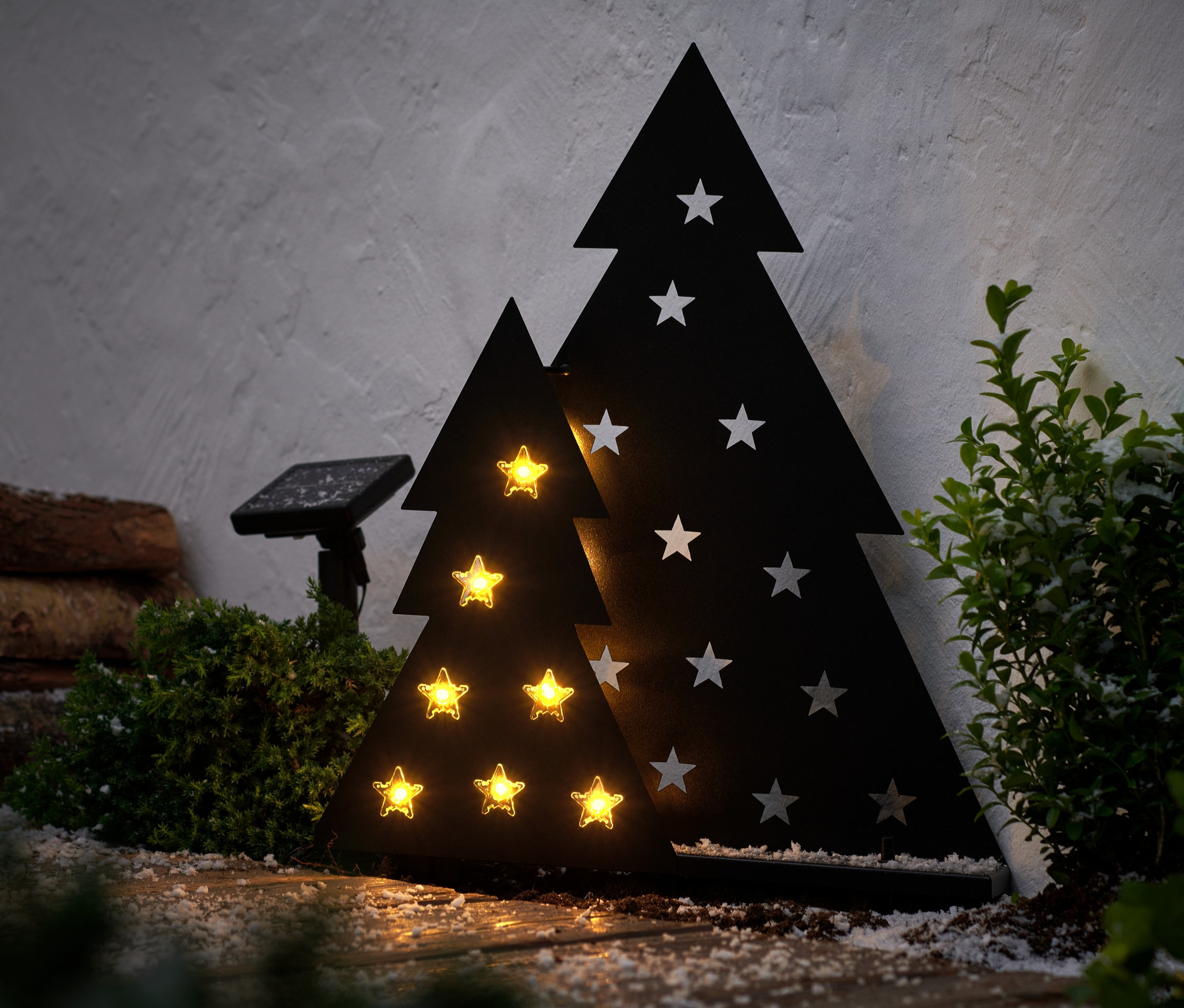 Zwei Solar-Leuchten »Metalltanne« mit Sternen stehen nebeneinander, eine größere und eine kleinere. Die kleinere leuchtet.
