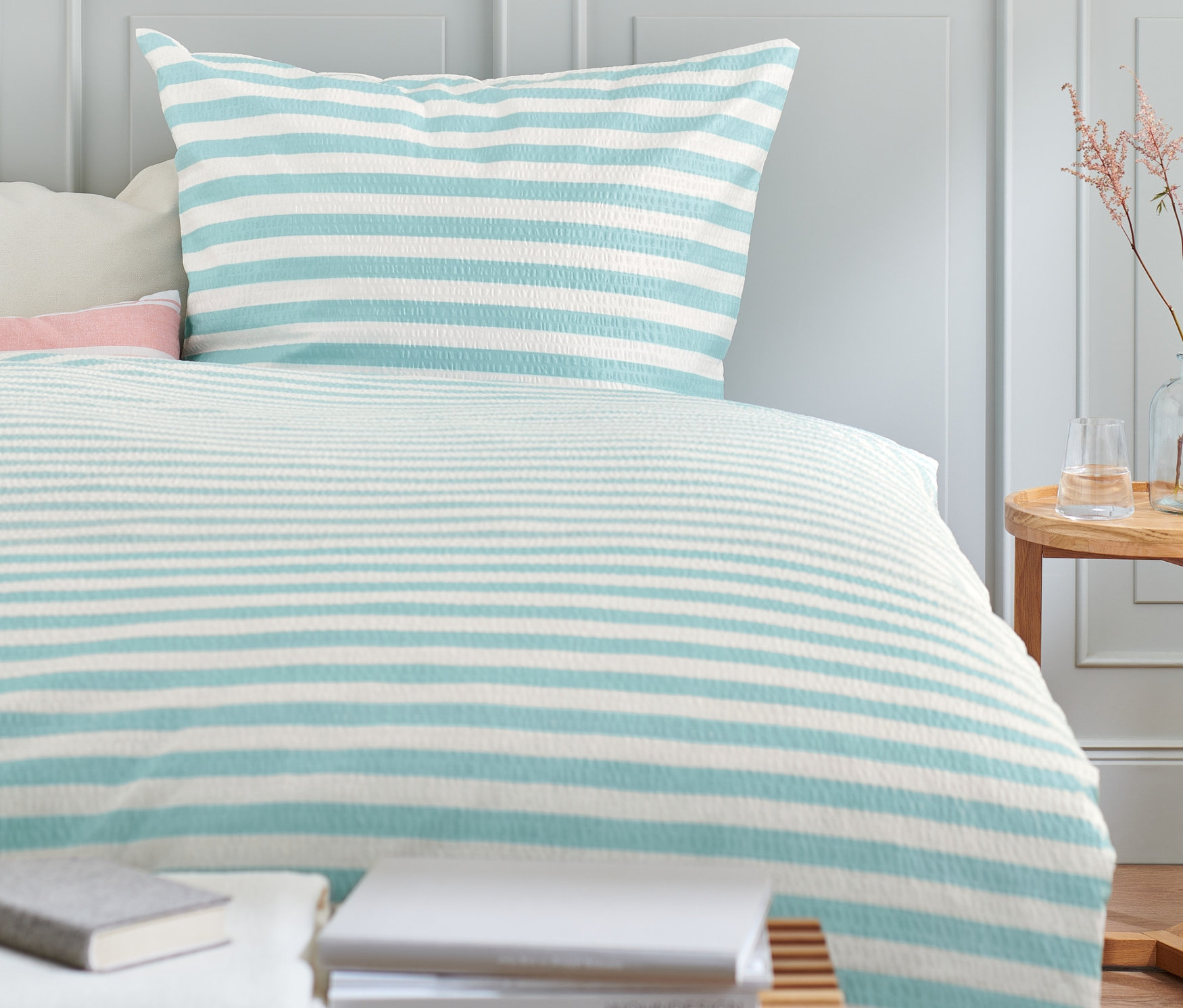 Seersucker-Bettwäsche mit blau-weißen Streifen auf einem Bett.