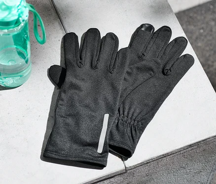 Auf einer Betonfläche liegen Laufhandschuhe und eine Wasserflasche.