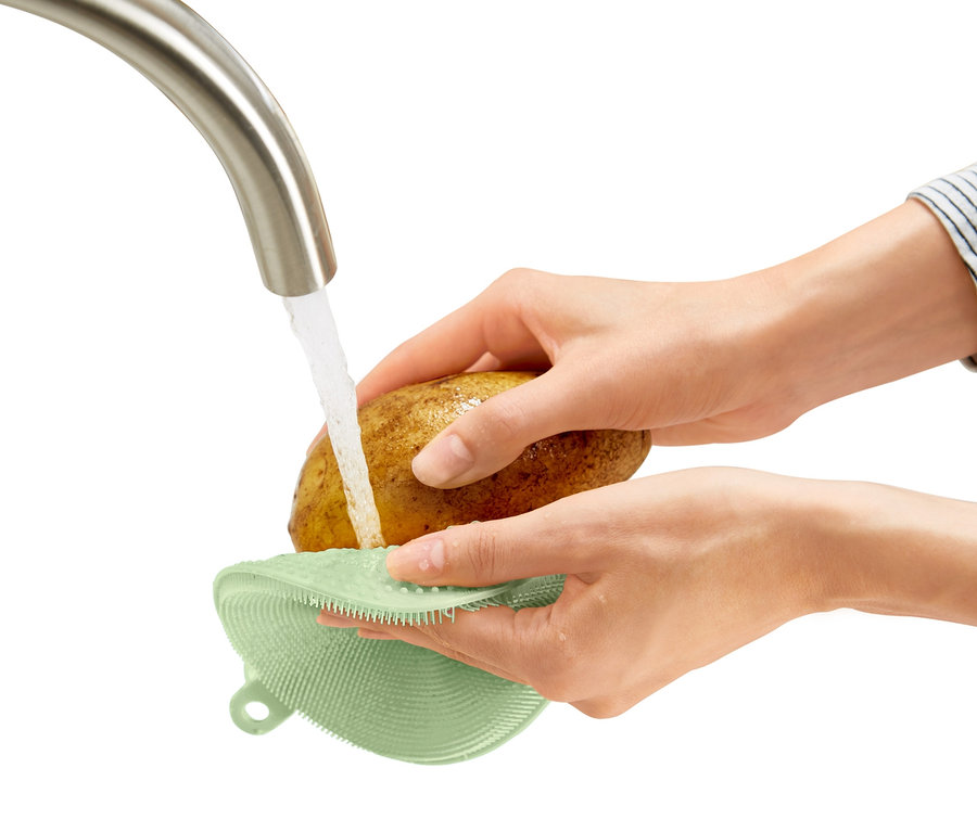 Eine Person wäscht eine Kartoffel unter fließendem Wasser mit einem 2 Silikon-Abwaschpad.