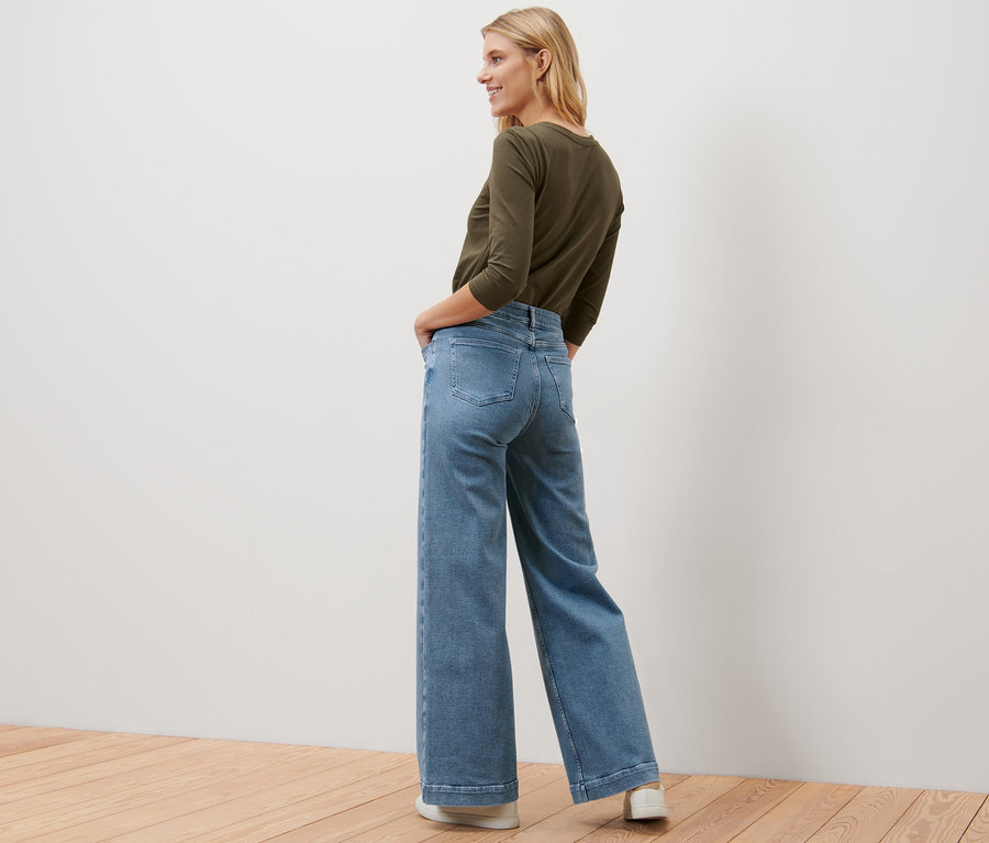 Blonde Frau posiert in Wide Leg Jeans – Fit »Viki« und olivfarbenem Oberteil.