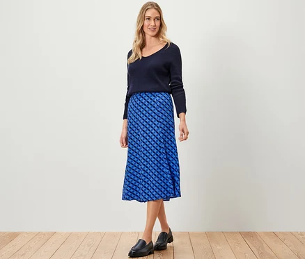 Frau posiert in dunkelblauem Pullover und blauem bedruckten Midirock.