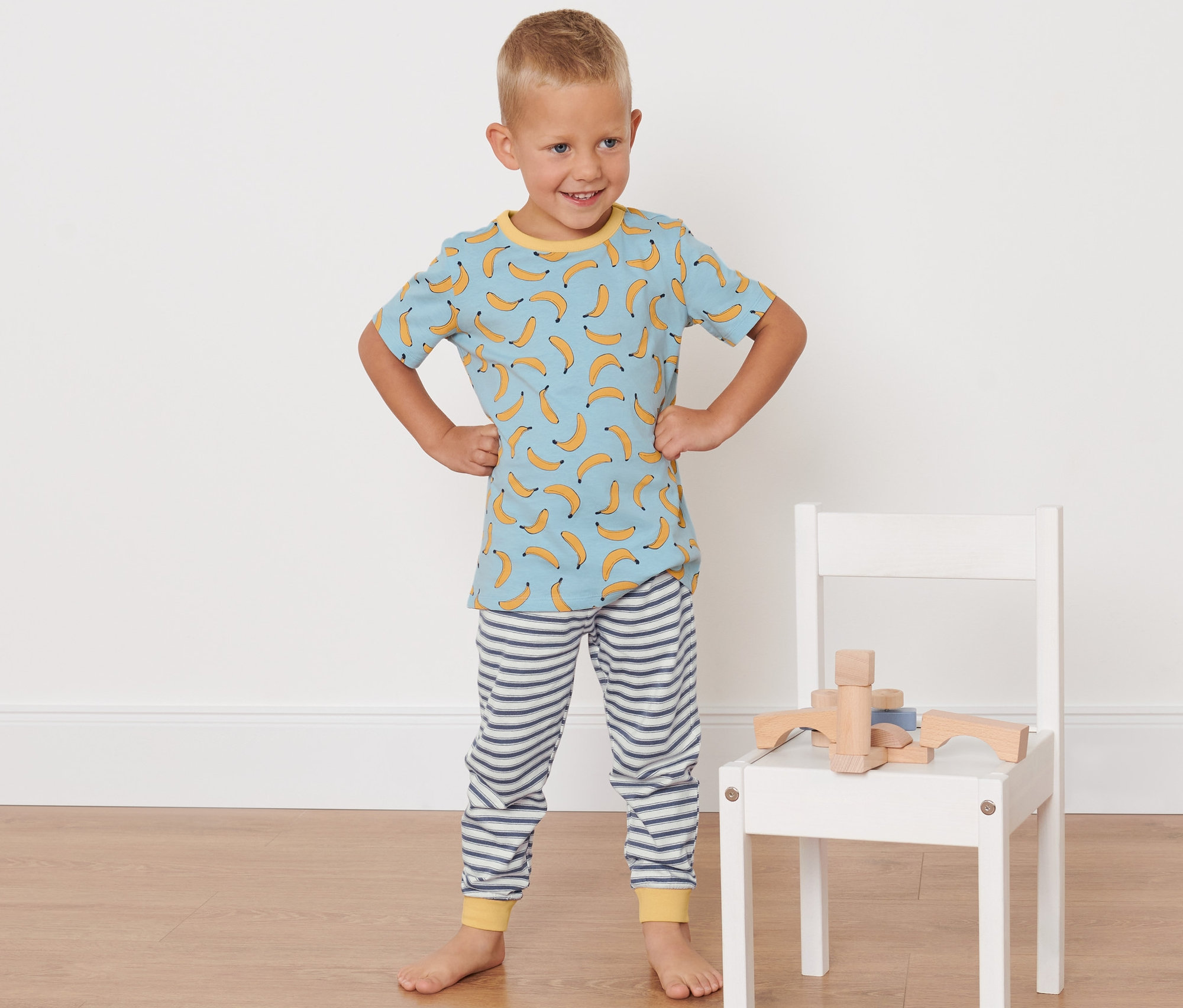 Junge posiert in seinem Bananen-Pyjama, 2 Kinder-Pyjamas, Bananen-Alloverprint.
