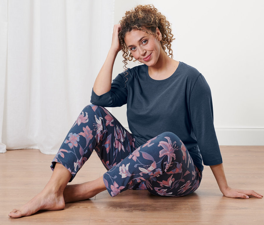 Eine Frau sitzt auf dem Boden und trägt einen Pyjama.