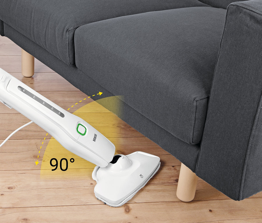 Ein weißer Dampfbesen reinigt unter einem grauen Sofa auf einem Holzboden.