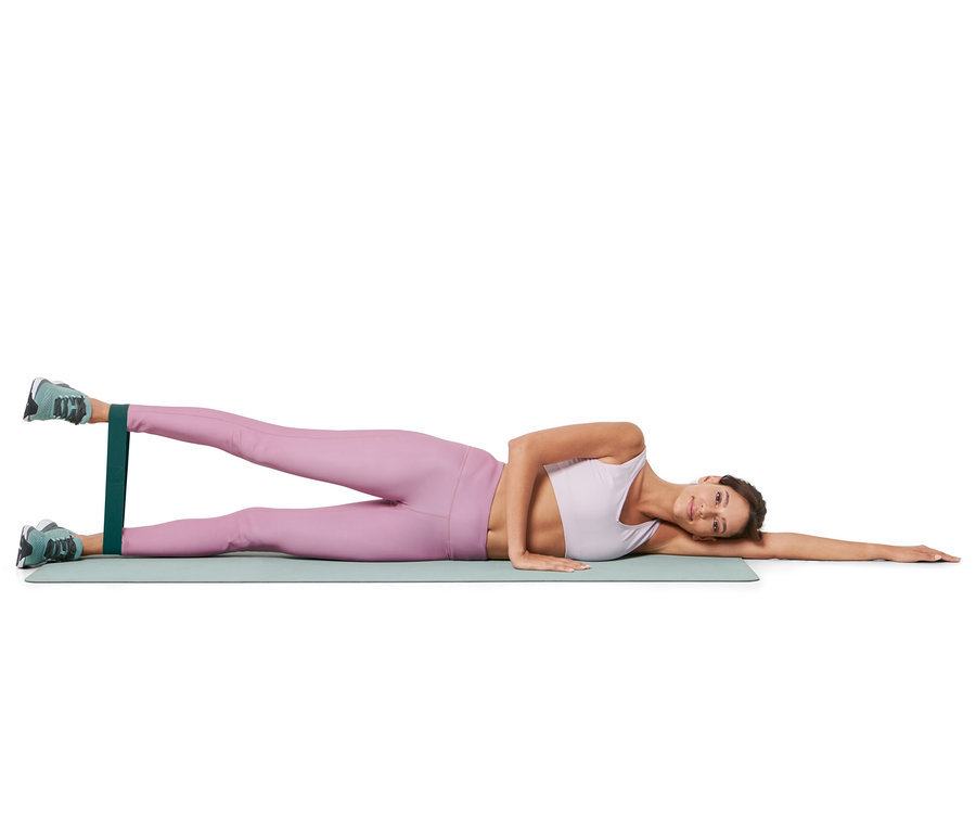 Frau liegt seitlich auf einer Matte und trainiert mit 3 Trainingsbändern.