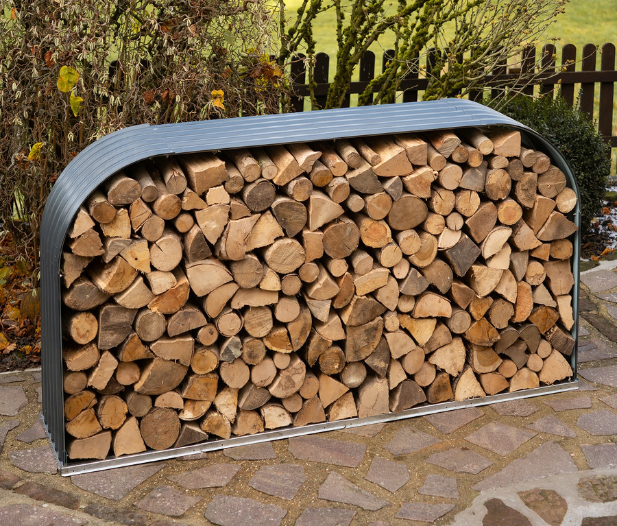 Ein Kaminholzregal gefüllt mit Holzscheiten steht im Freien auf Steinplatten.