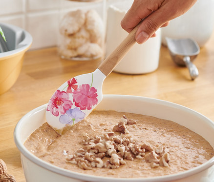 Frau rührt Teig mit einem Teigschaber.