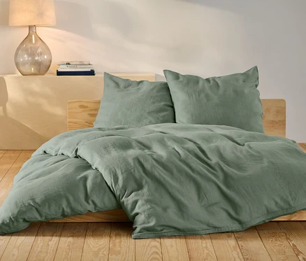 Grüne Leinen-Bettwäsche in Normalgröße und Übergröße auf einem Bett.