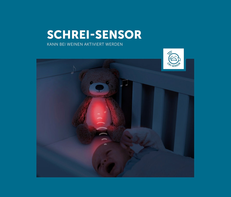 In einem Gitterbett liegt ein weinendes Baby unter einem rot leuchtenden Zazu Nachtlicht »Brody der Bär«.