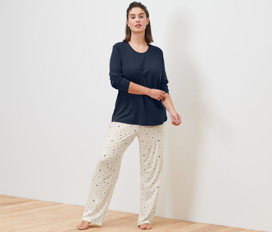 Frau steht und trägt einen creme Pyjama.