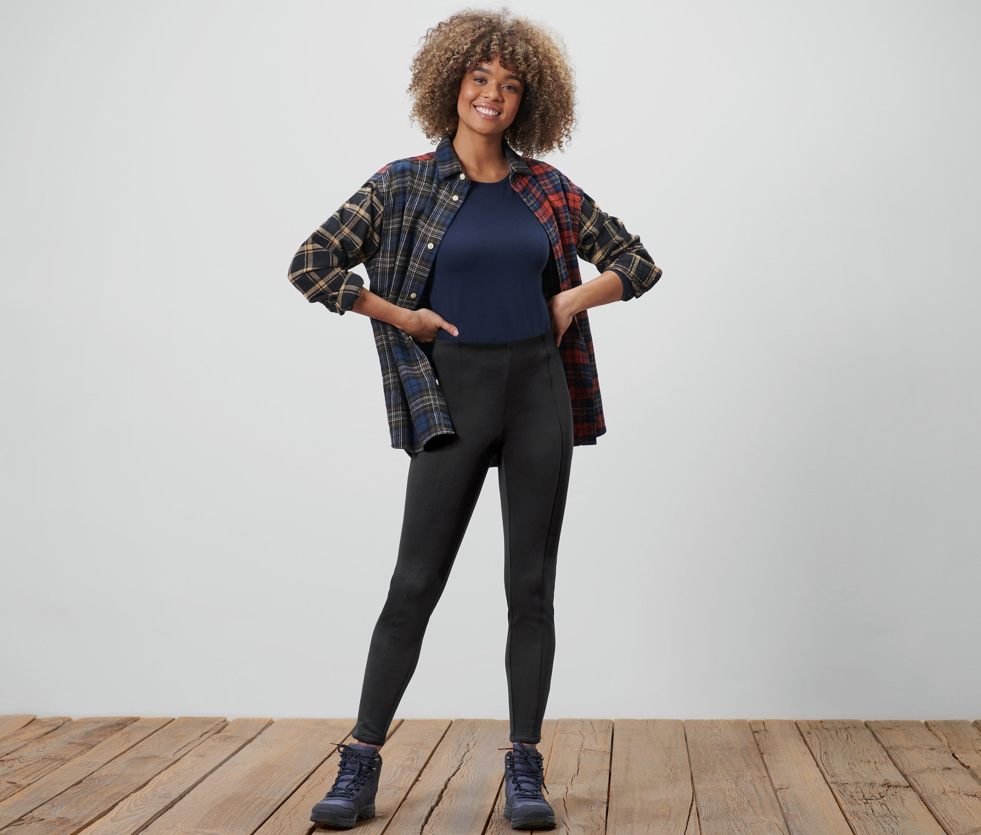 Frau posiert in Thermotights, T-Shirt und Flanellhemd.