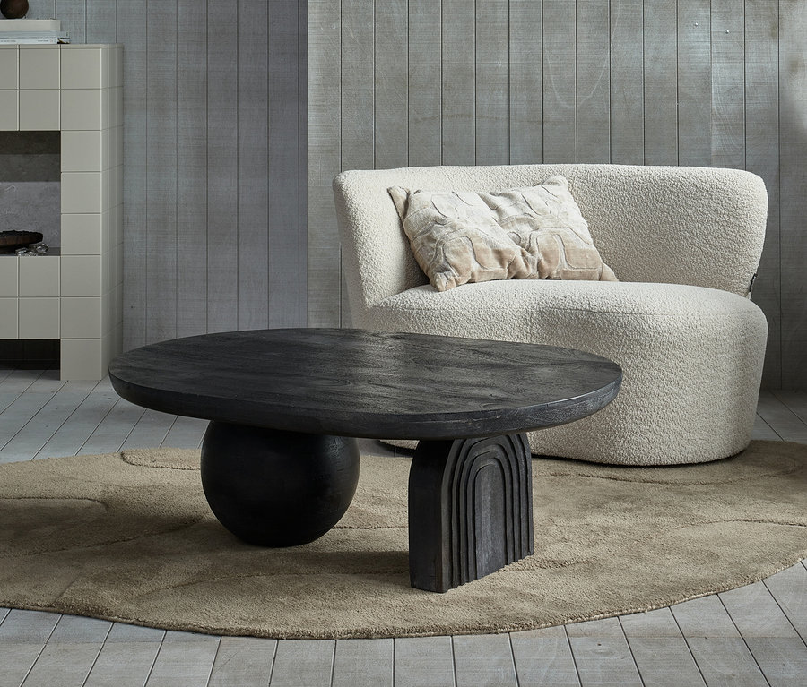 Wohnzimmer mit beigem Sessel, braunem, organischem Woood Teppich Alya, 170 x 240 cm, und schwarzem Woood Couchtisch Steppe.