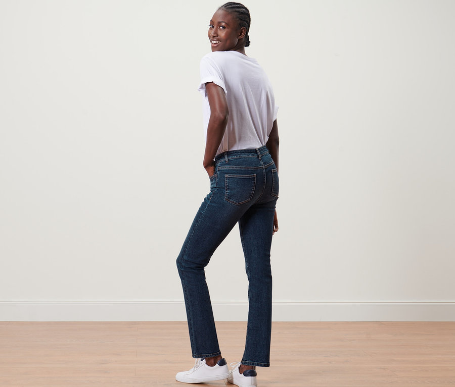 Frau posiert und trägt Straight-Denim »Fit Kira«, ein weißes T-Shirt und Turnschuhe.