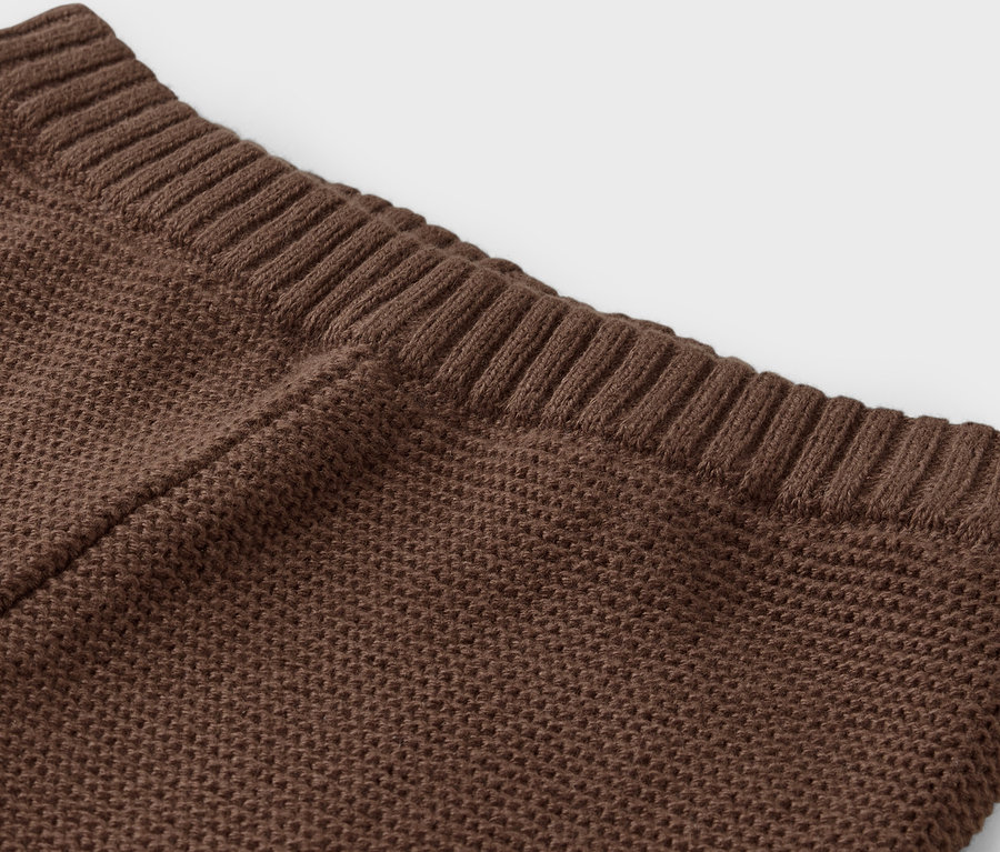 Detailaufnahme eines braunen Strickstoffs mit geripptem Saum.