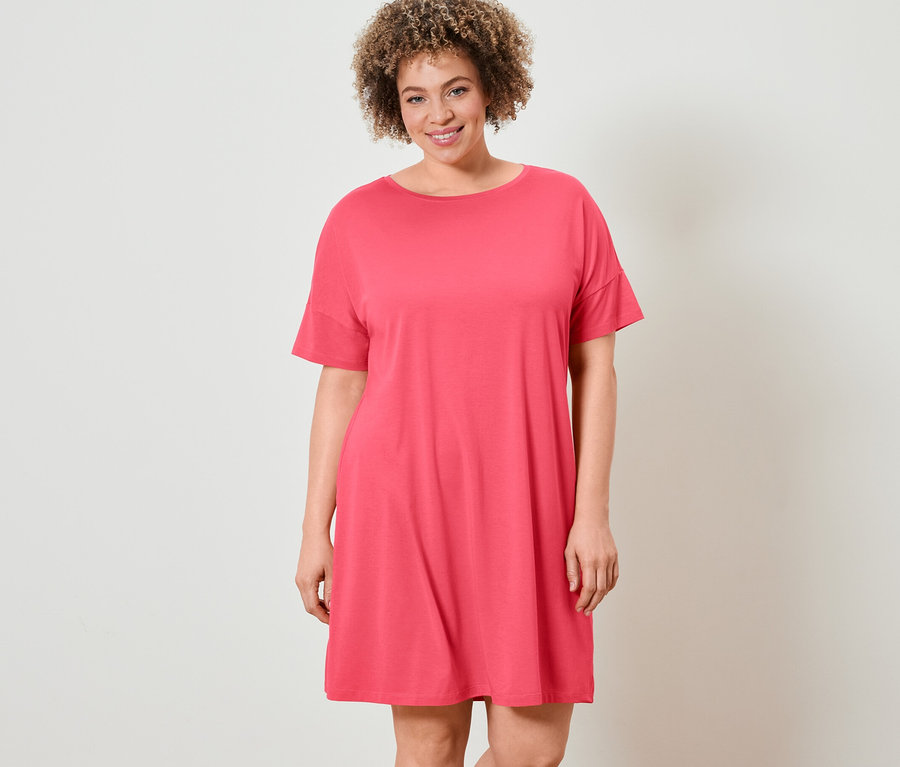 Frau mit lockigem Haar posiert in einem Nachthemd.