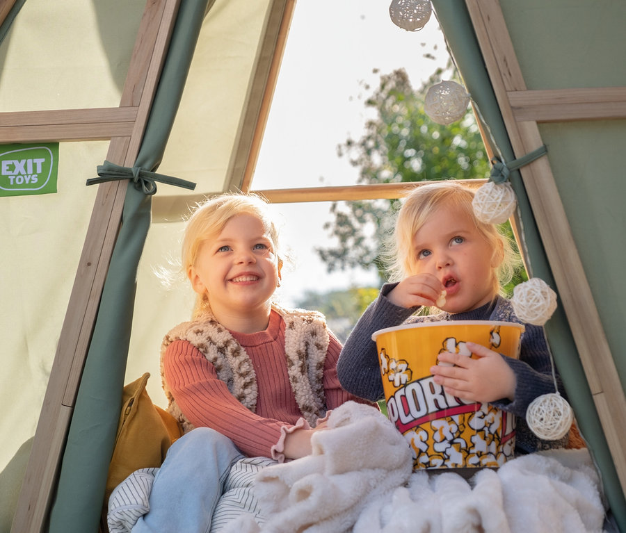 Zwei Mädchen sitzen im EXIT Spielhaus »Yuki 300« mit Rutsche und essen Popcorn.