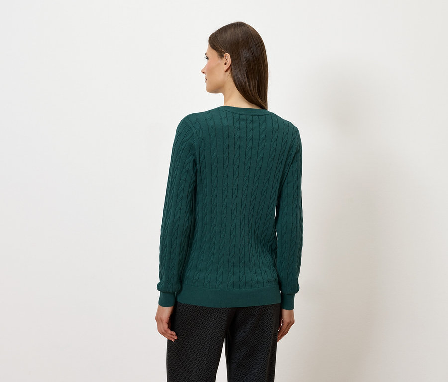 Rückansicht einer Frau in einem grünen Pullover und einer dunklen Hose.