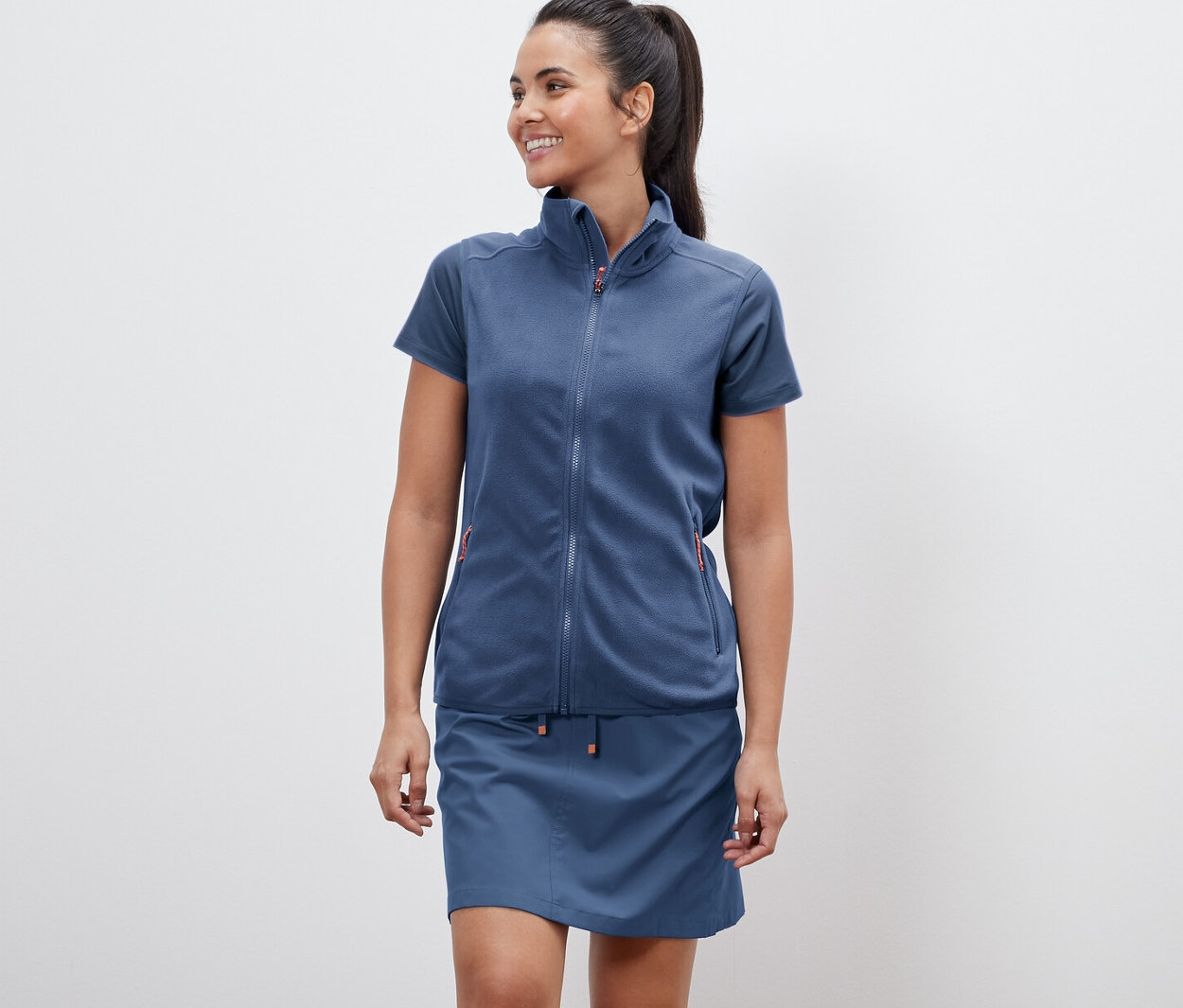 Frau trägt eine Fleece-Weste und einen Rock.