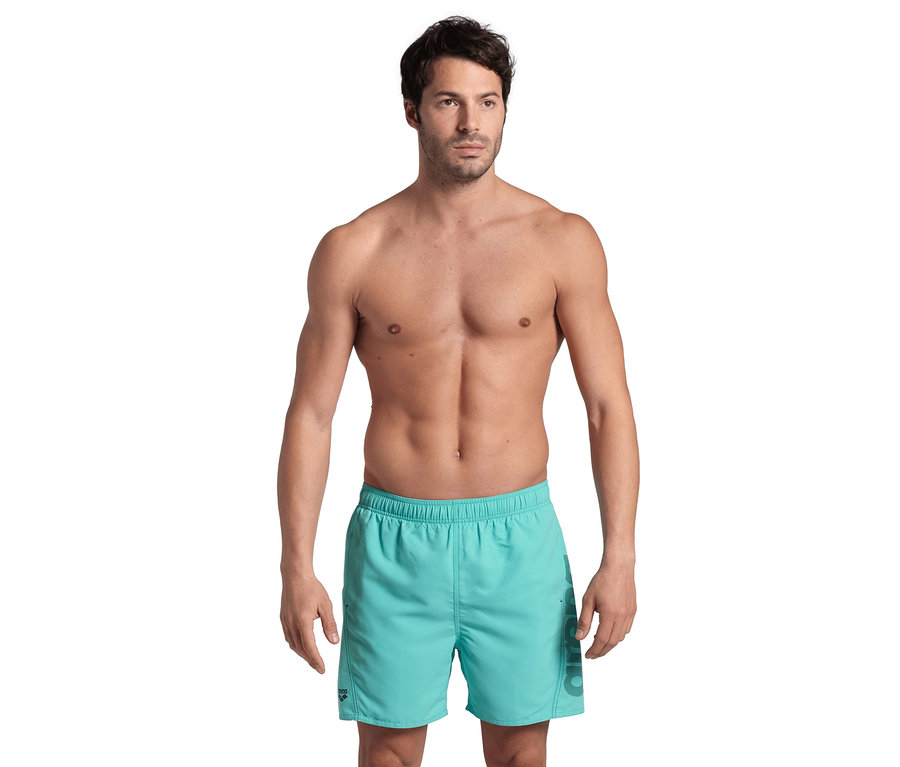 Mann posiert oberkörperfrei in hellblauen Arena Badeshorts Fundamentals Logo.