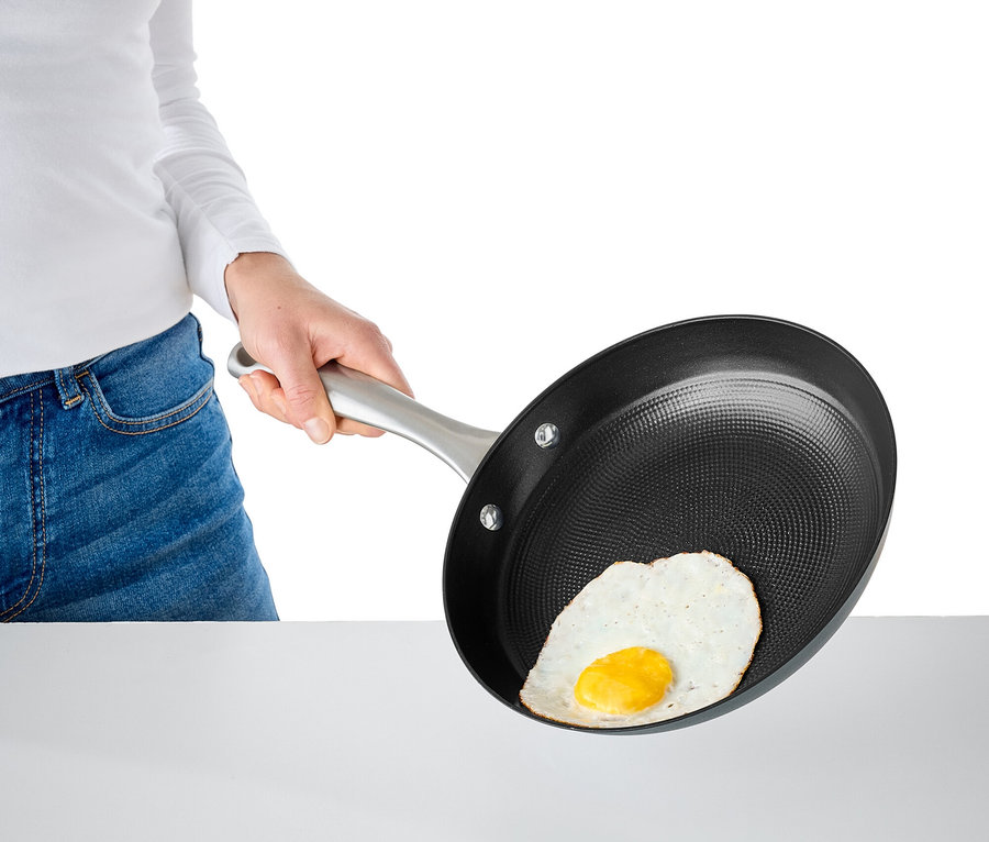 Frau hält eine Bratpfanne mit einem Spiegelei.