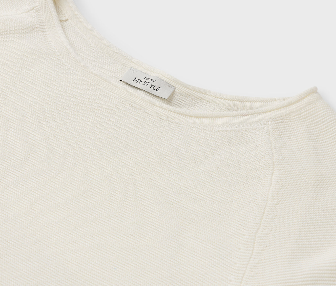 Detail eines cremefarbenen Pullovers mit MY STYLE Etikett.