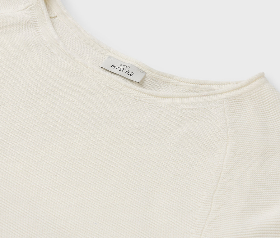 Detail eines cremefarbenen Pullovers mit MY STYLE Etikett.