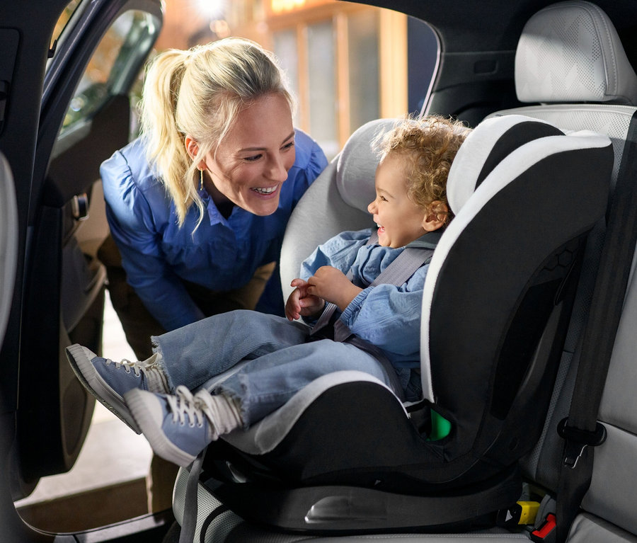 Eine Mutter schaut auf ein lachendes Kind im Maxi-Cosi Kinder-Autositz »Titan S«, i-Size im Auto.