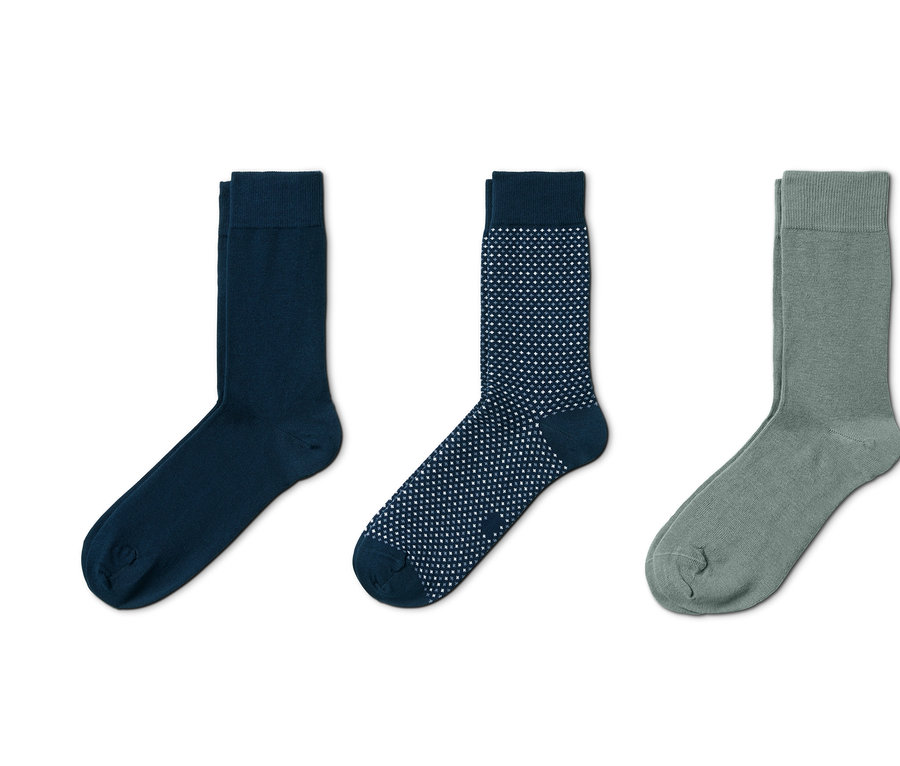 Drei Paar Socken: Dunkelblaue, blaue mit weißen Punkten und graugrüne.