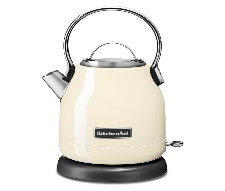 Ein KitchenAid Wasserkocher in Creme steht auf einer schwarzen Basis.