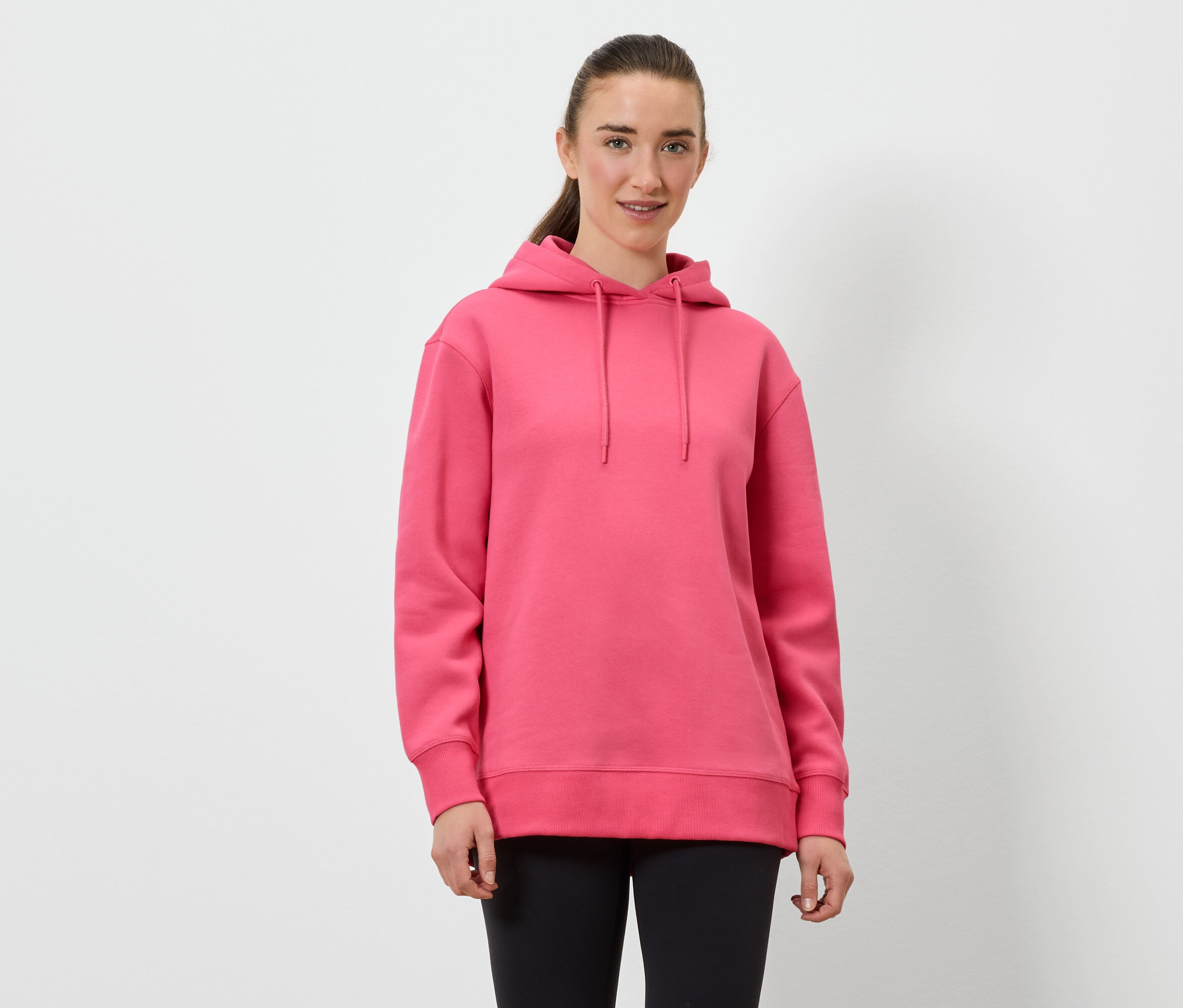 Frau trägt einen rosa Hoodie und schwarze Leggings.