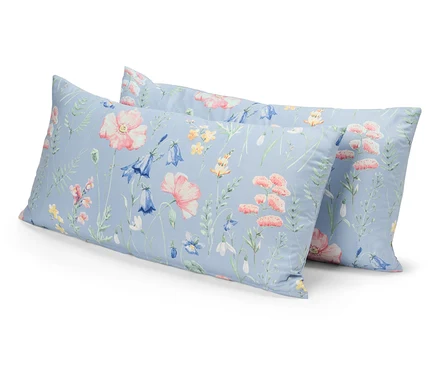 Zwei Kissen mit Blumenmuster auf blauem Grund liegen übereinander.