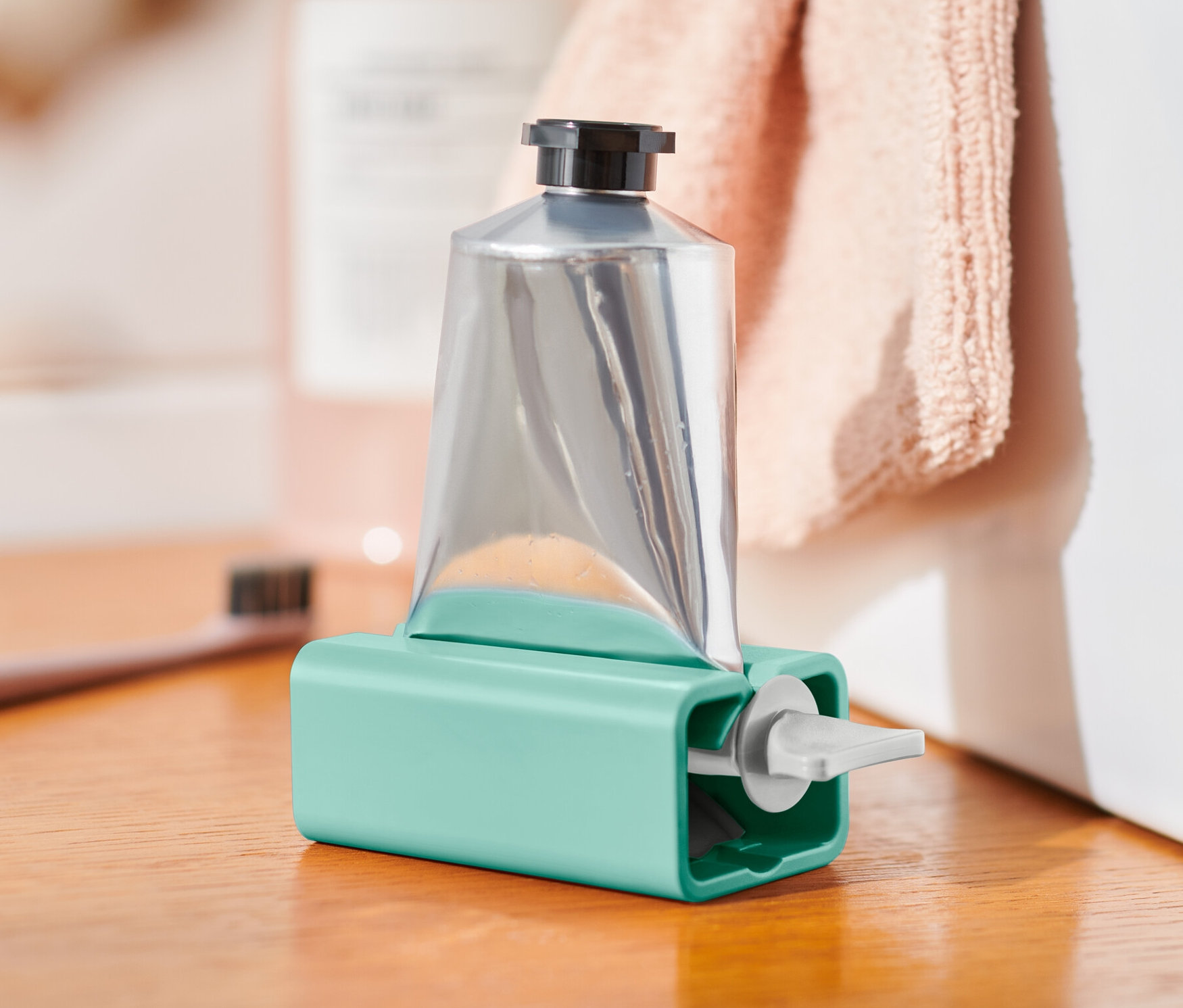 Silberne Tube in türkisfarbenem Tubenpresser auf einem Holzschrank.