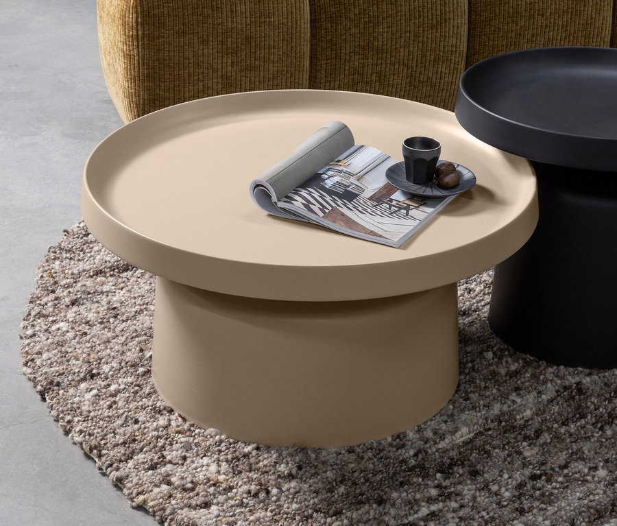Auf einem braunen Teppich stehen zwei Tische, auf dem sandfarbenen Woood Peer Beistelltisch liegen eine Zeitschrift und eine Tasse mit Untertasse.